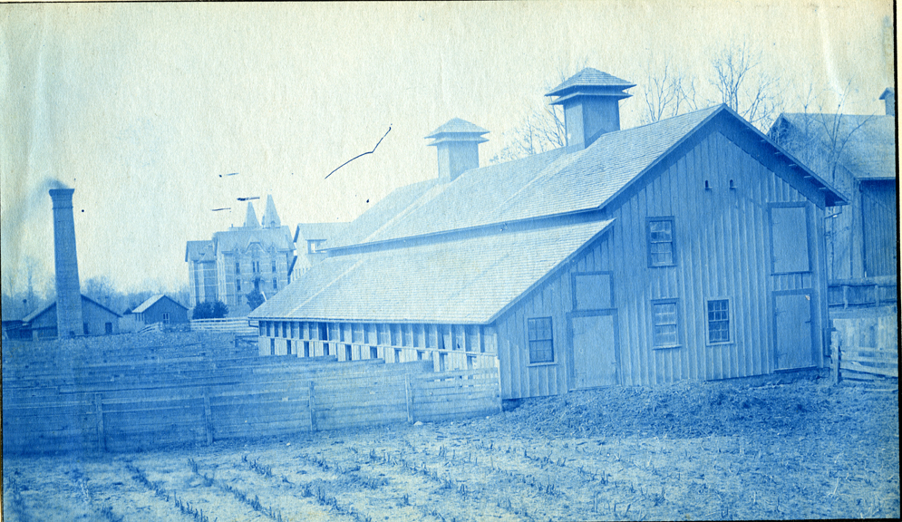 73. A barn and field with the Boiler House and Wells Hall (1), circa 1888.