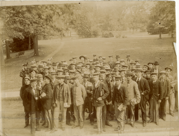 Male students stand together outside on campus