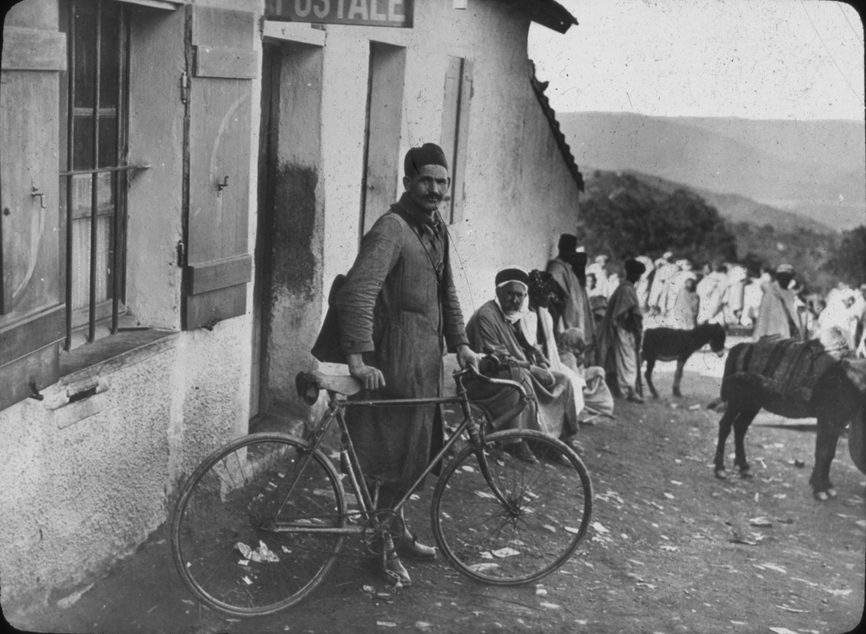 Algerian (?) man outside building with bike, undated