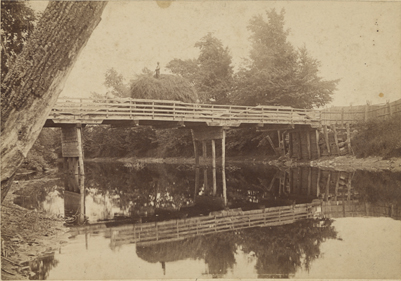 Farmer crossing bridge, date unknown