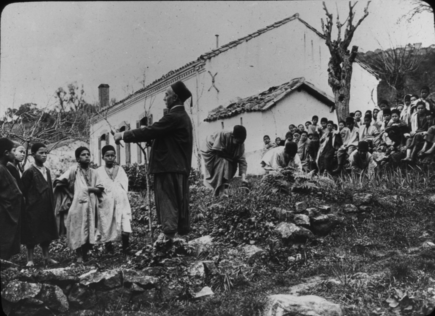 A large group of youths in Algeria watch an older man, undated