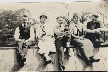 Five students sitting on a wall, date unknown