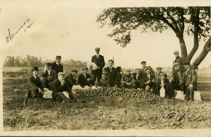 Students sit next to a pile of apples, 1912