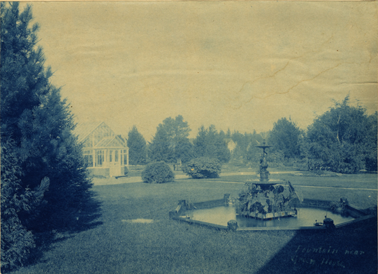 Campus fountain near a greenhouse, date unknown