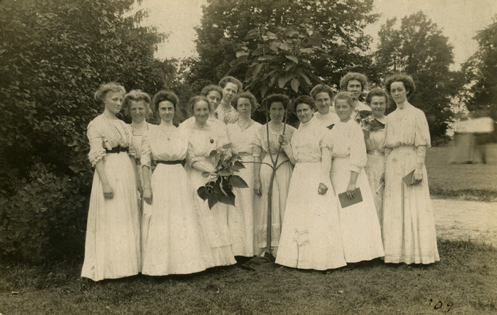 Young women pose by a tree, date unknown