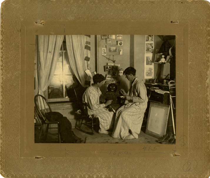 Two Men Feeding a Doll in their Dorm Room
