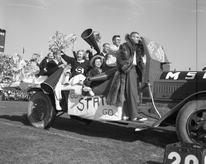 Cheerleading team in parade car, 1954