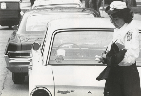 Parking officer writing ticket, 1966-1967