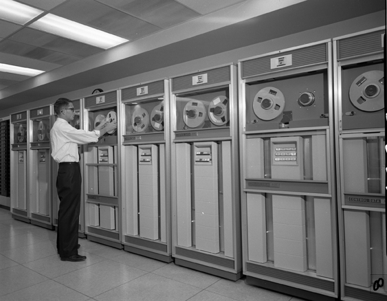 A man examines magnetic tape on a computer